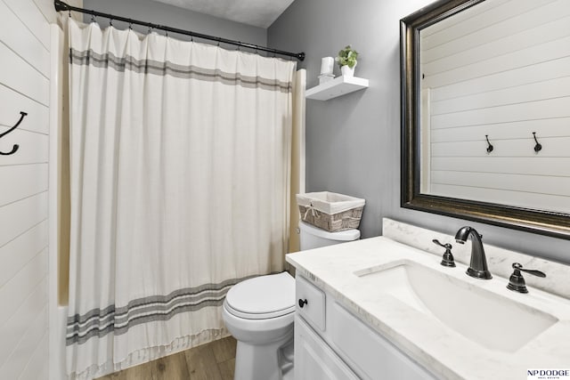 full bathroom with wood finished floors, toilet, vanity, and curtained shower