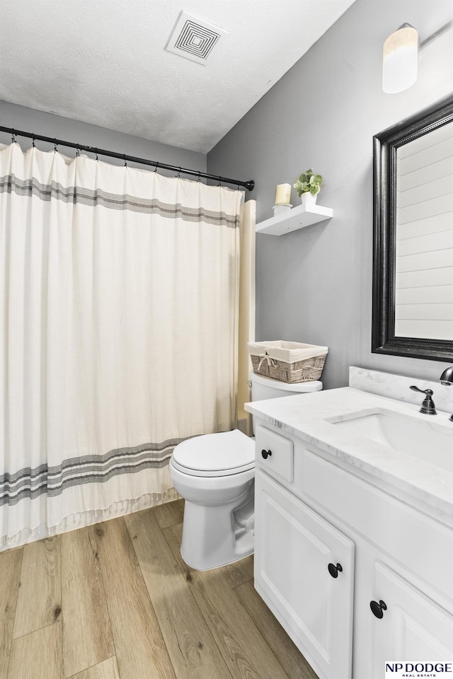 bathroom with wood finished floors, toilet, vanity, and a shower with shower curtain