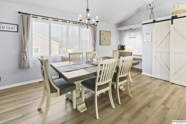 dining area with a barn door, a chandelier, light wood-style floors, lofted ceiling, and baseboards