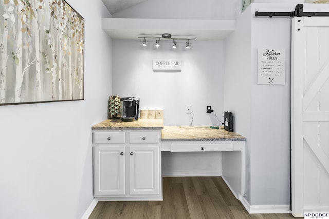 bar area featuring dark wood-type flooring, baseboards, and a barn door