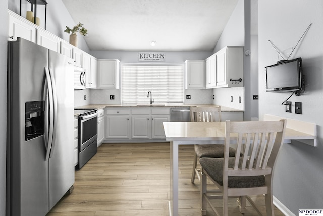 kitchen with appliances with stainless steel finishes, a sink, light wood finished floors, light countertops, and white cabinets