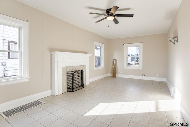 unfurnished living room featuring baseboards, a ceiling fan, light tile patterned flooring, visible vents, and a tile fireplace