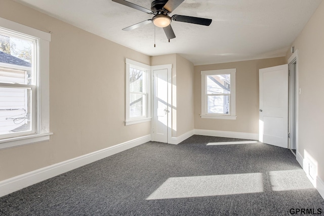 empty room featuring visible vents, baseboards, dark carpet, and a ceiling fan