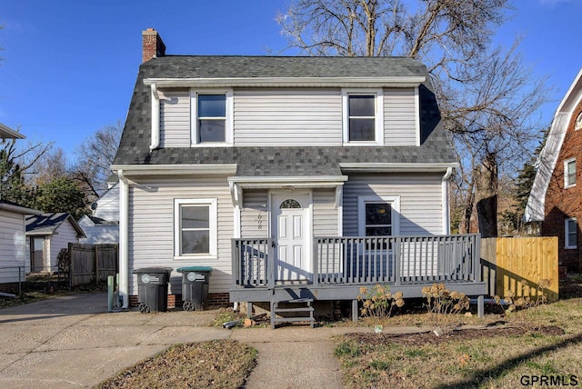 view of front of house with fence, roof with shingles, and a chimney