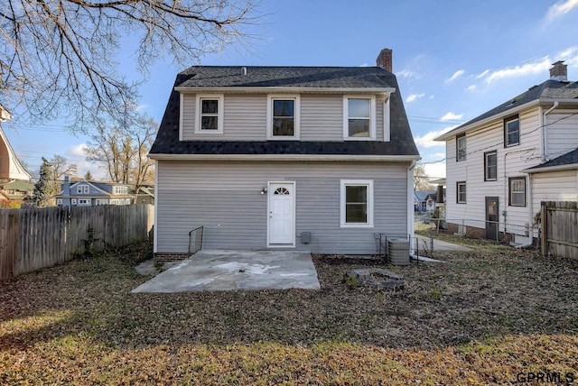 rear view of house featuring cooling unit, a fenced backyard, a patio, roof with shingles, and a chimney