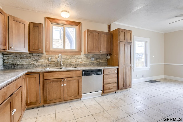 kitchen with baseboards, backsplash, brown cabinetry, stainless steel dishwasher, and a sink