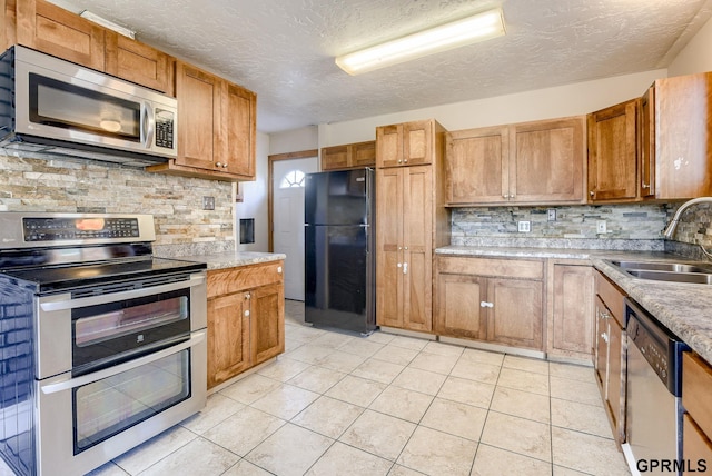 kitchen featuring a textured ceiling, a sink, backsplash, and appliances with stainless steel finishes