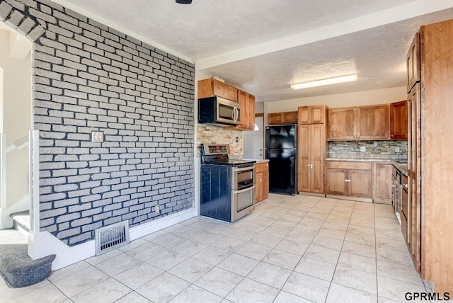 kitchen with light tile patterned floors, a textured ceiling, visible vents, appliances with stainless steel finishes, and decorative backsplash