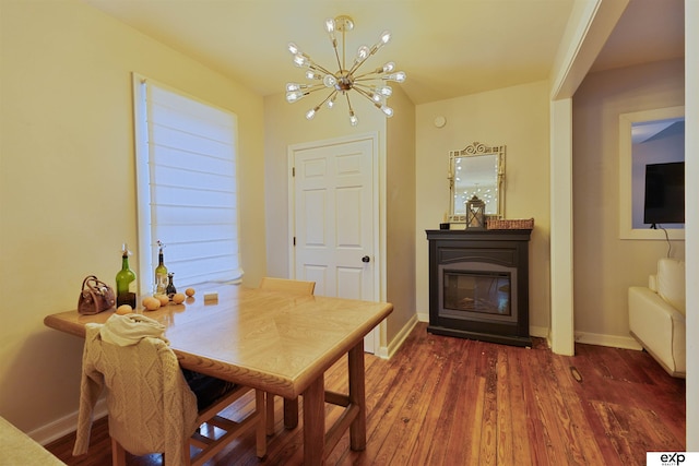 dining area with an inviting chandelier, baseboards, a glass covered fireplace, and wood finished floors