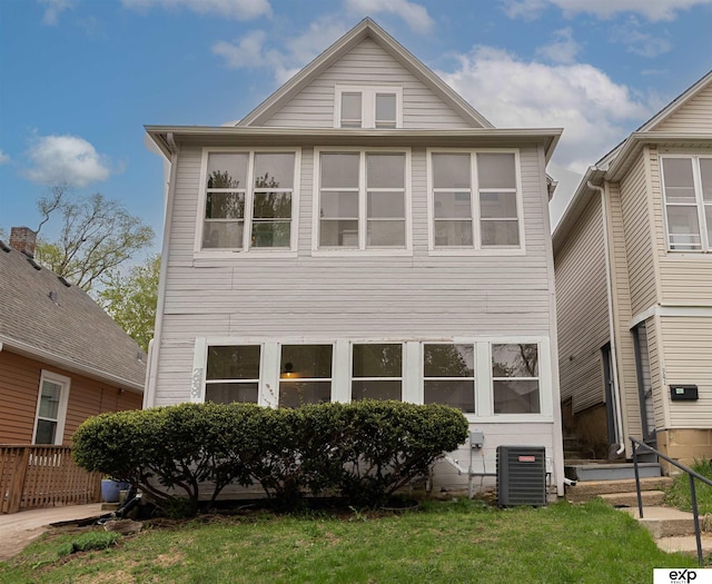 view of front of house with central air condition unit and a front lawn
