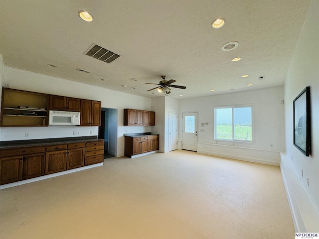 kitchen featuring dark countertops, visible vents, white microwave, and recessed lighting