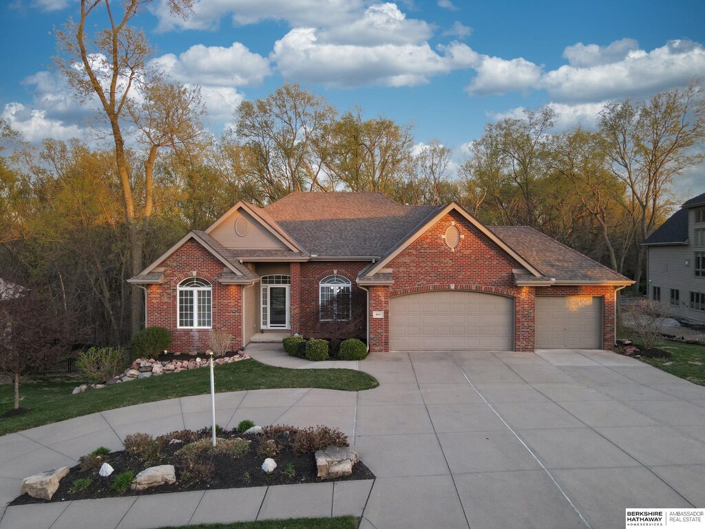 ranch-style home with a front lawn, driveway, brick siding, and a garage