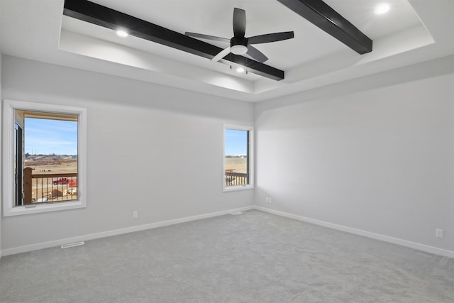 empty room featuring a ceiling fan, a tray ceiling, beamed ceiling, baseboards, and carpet flooring