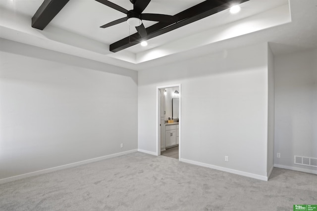 unfurnished bedroom with a raised ceiling, visible vents, beam ceiling, baseboards, and light colored carpet