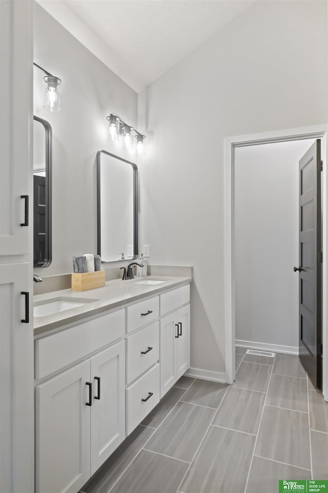 full bath with baseboards, a sink, and double vanity
