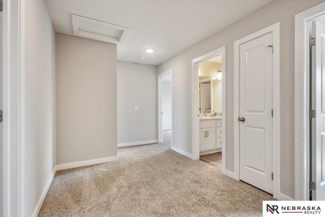 unfurnished bedroom with light colored carpet, baseboards, attic access, and ensuite bathroom