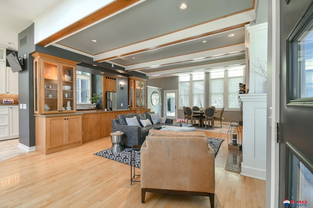 living room featuring a healthy amount of sunlight, light wood-style floors, visible vents, and beam ceiling