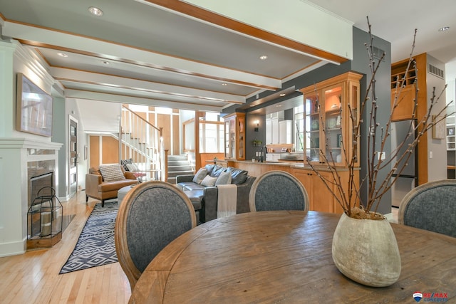 dining room with a high end fireplace, visible vents, light wood finished floors, and stairs
