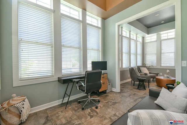 office area with baseboards and stone finish floor