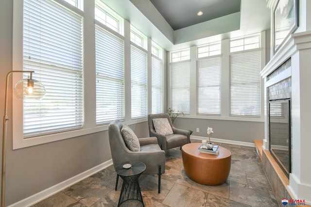 living area with baseboards, stone tile floors, and a wealth of natural light