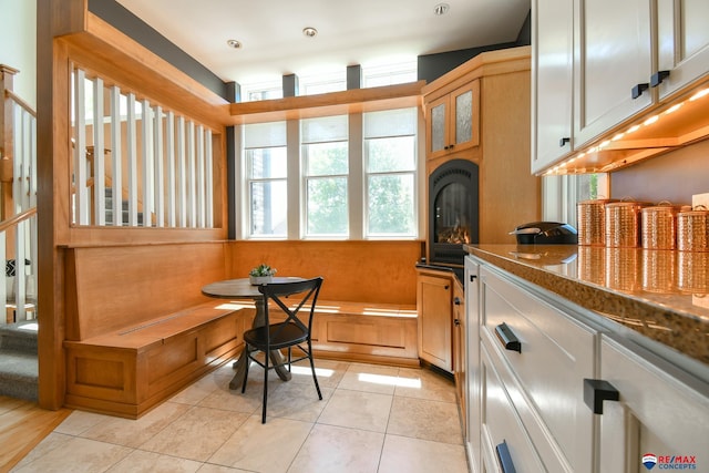 interior space featuring light tile patterned floors, dark countertops, and glass insert cabinets