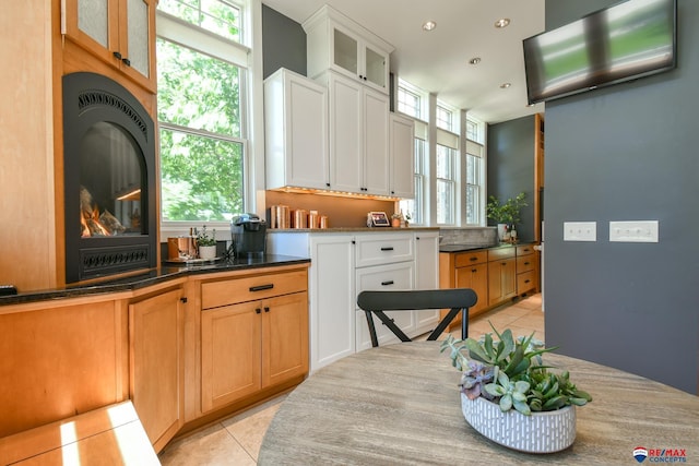 kitchen with light tile patterned flooring, glass insert cabinets, and a wealth of natural light