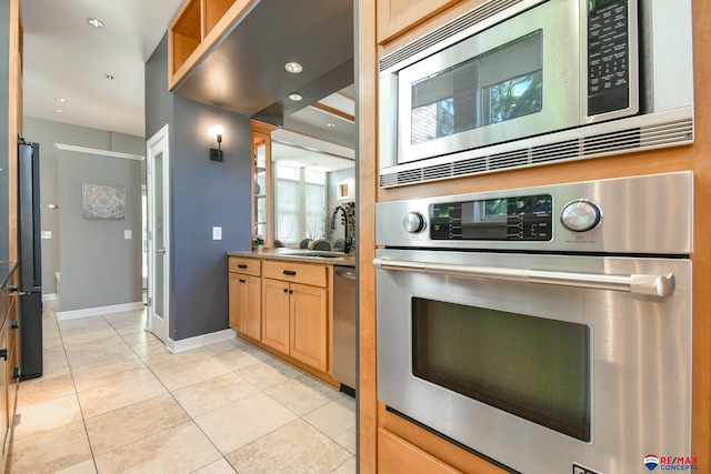 kitchen featuring a sink, light tile patterned flooring, baseboards, recessed lighting, and appliances with stainless steel finishes