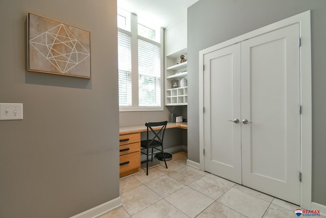 home office with built in desk, baseboards, and light tile patterned floors