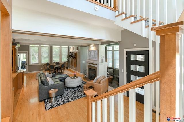 living area featuring a towering ceiling, wood finished floors, a fireplace, and stairs
