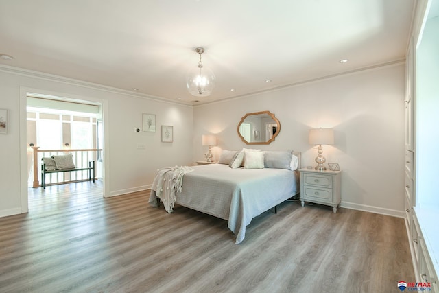 bedroom with a chandelier, light wood-style flooring, crown molding, and baseboards