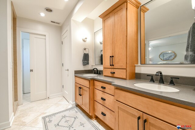 bathroom featuring tile patterned flooring, a sink, visible vents, and double vanity