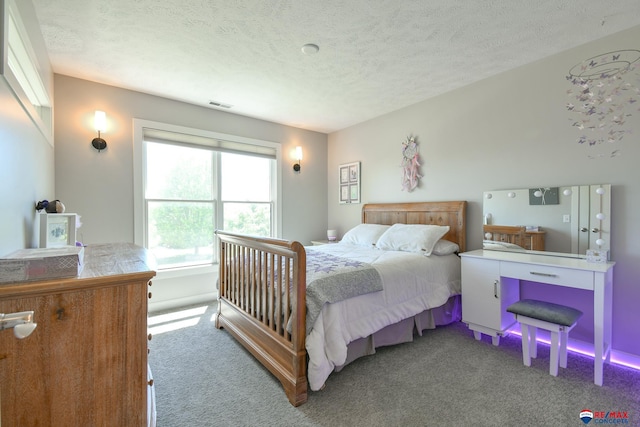 carpeted bedroom featuring a textured ceiling and visible vents
