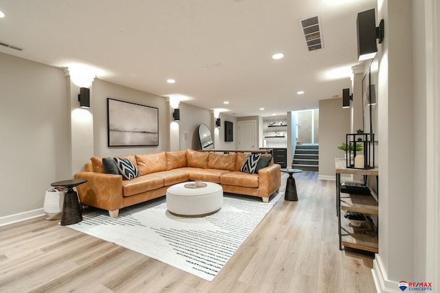 living room featuring recessed lighting, light wood-style floors, visible vents, and stairs