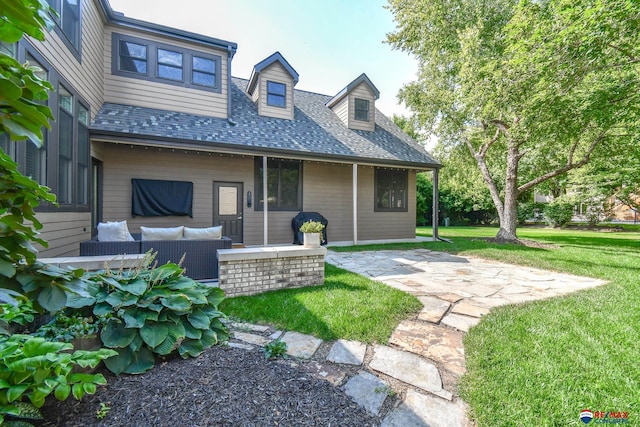 rear view of property featuring a lawn, a shingled roof, a patio, and an outdoor living space