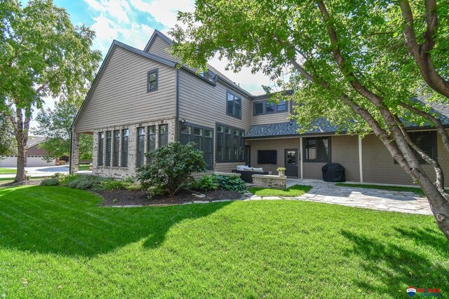 back of property featuring a patio area, brick siding, a yard, and an outdoor hangout area