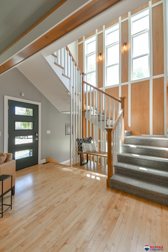 entryway featuring baseboards, vaulted ceiling, hardwood / wood-style flooring, and stairs