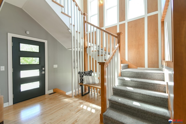 foyer entrance with lofted ceiling, baseboards, wood finished floors, and stairway