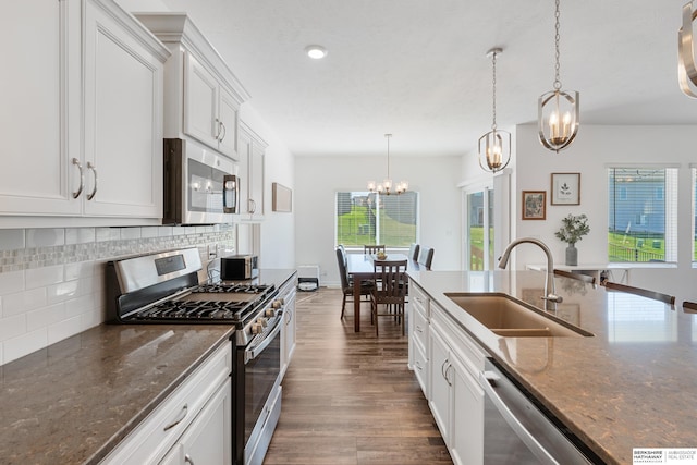 6315 N Hws Cleveland Blvd, Omaha, NE 68116 - kitchen with backsplash, a sink, dark wood-type flooring, appliances with stainless steel finishes, and a notable chandelier