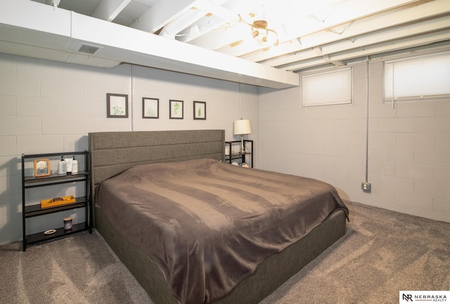 bedroom featuring concrete block wall, visible vents, and dark carpet