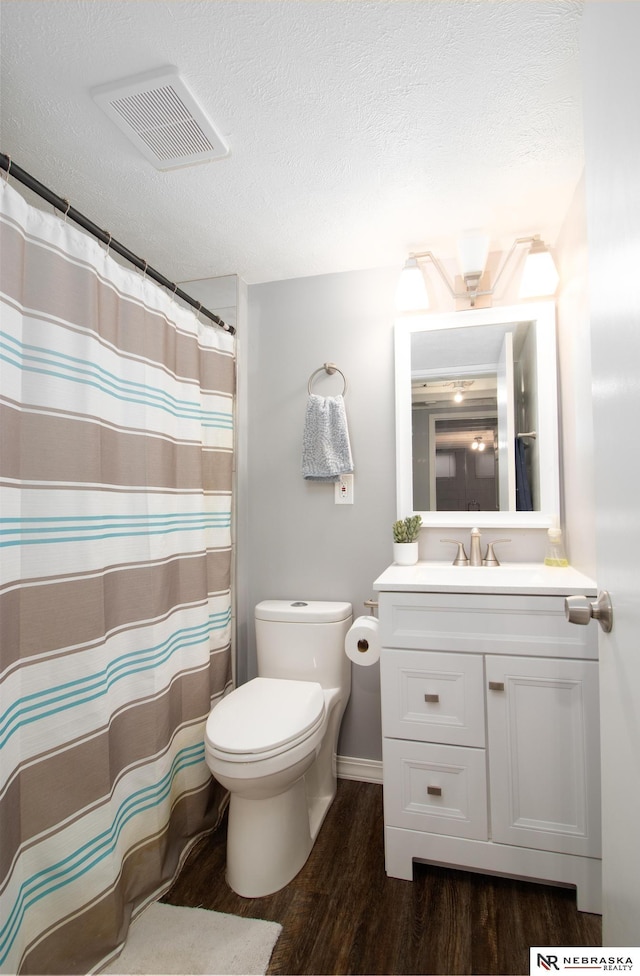 full bath featuring wood finished floors, a textured ceiling, vanity, toilet, and visible vents