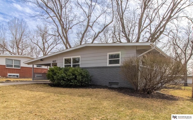 view of side of property with brick siding, a lawn, and fence