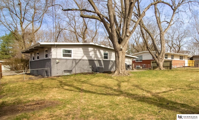 exterior space featuring a lawn, central AC unit, brick siding, and fence