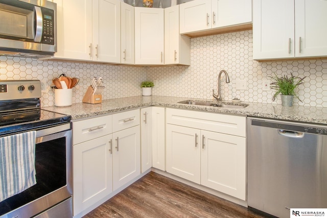 kitchen featuring light stone countertops, stainless steel appliances, dark wood-style floors, and a sink