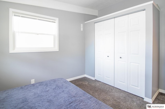 unfurnished bedroom with dark carpet, baseboards, and a closet