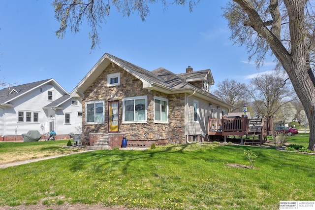 view of front of home featuring a chimney, stone siding, a front lawn, and a deck