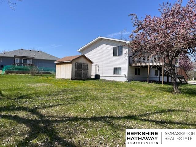 2331 W C Ct, Lincoln, NE 68522 - back of house featuring an outdoor structure, a storage unit, a wooden deck, and a yard