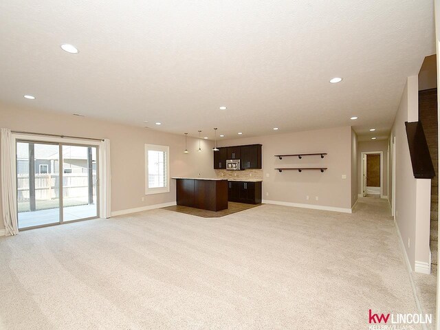 unfurnished living room featuring baseboards, light carpet, and recessed lighting