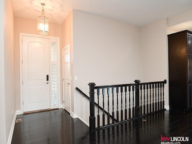 entrance foyer featuring an inviting chandelier, baseboards, and dark wood finished floors