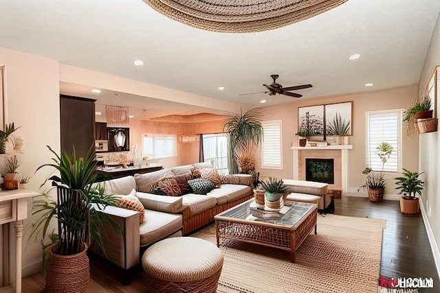 living room featuring dark wood-type flooring, a ceiling fan, and plenty of natural light