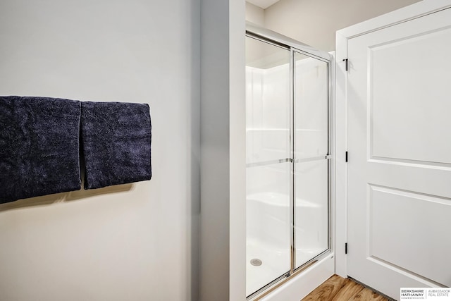 full bathroom featuring wood finished floors and a stall shower